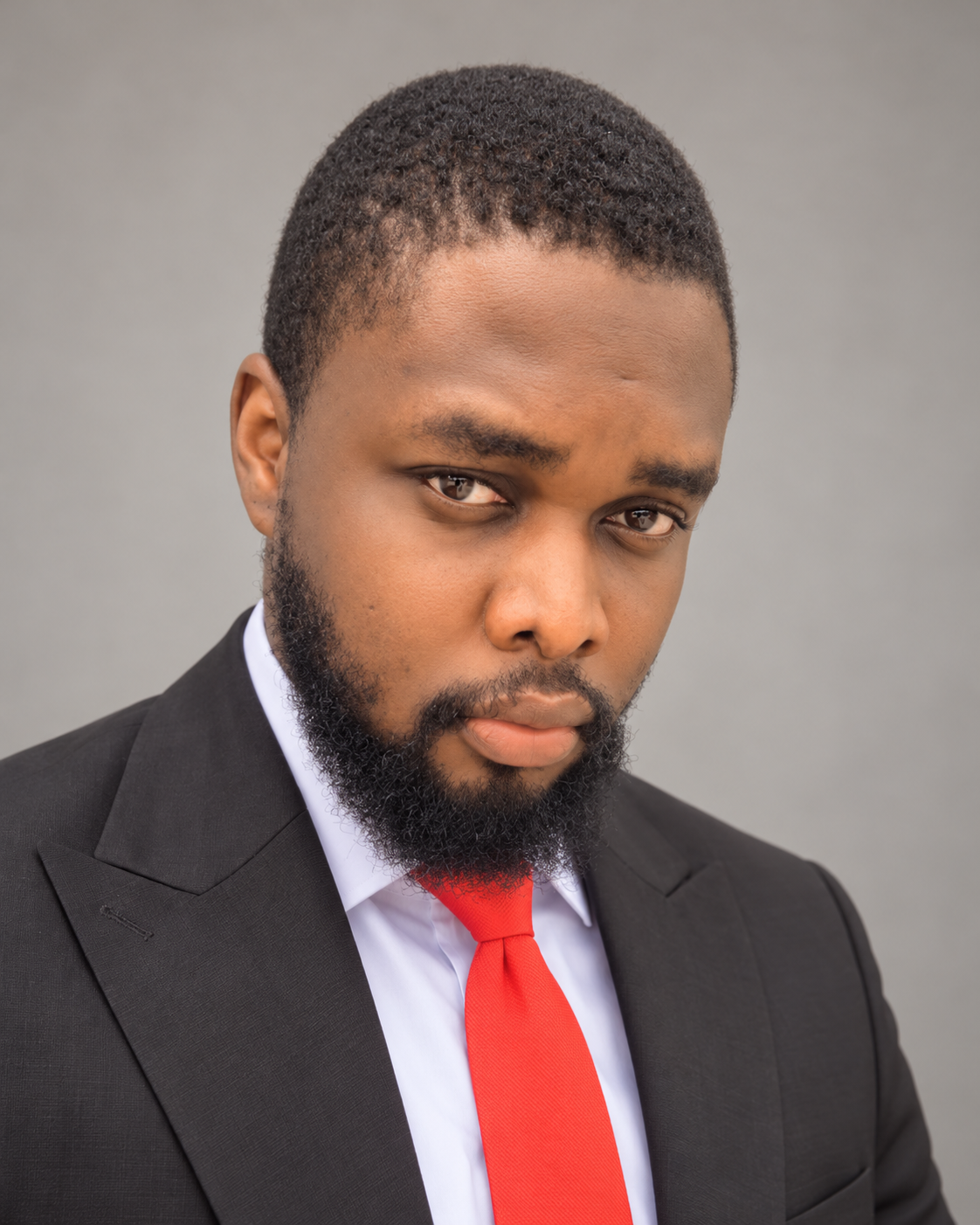 Oghene Akpomedaye Napoleon, founder of PrimeAdStudio, wearing a dark suit and red tie